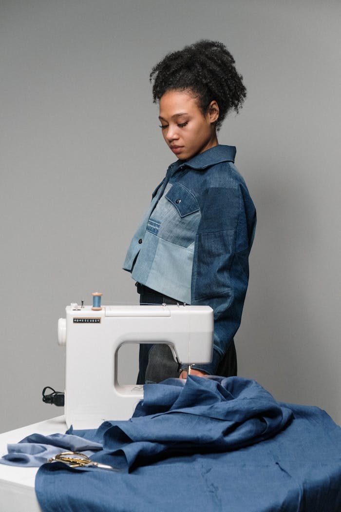 Portrait of a fashion designer working with a sewing machine and blue fabric in a studio.